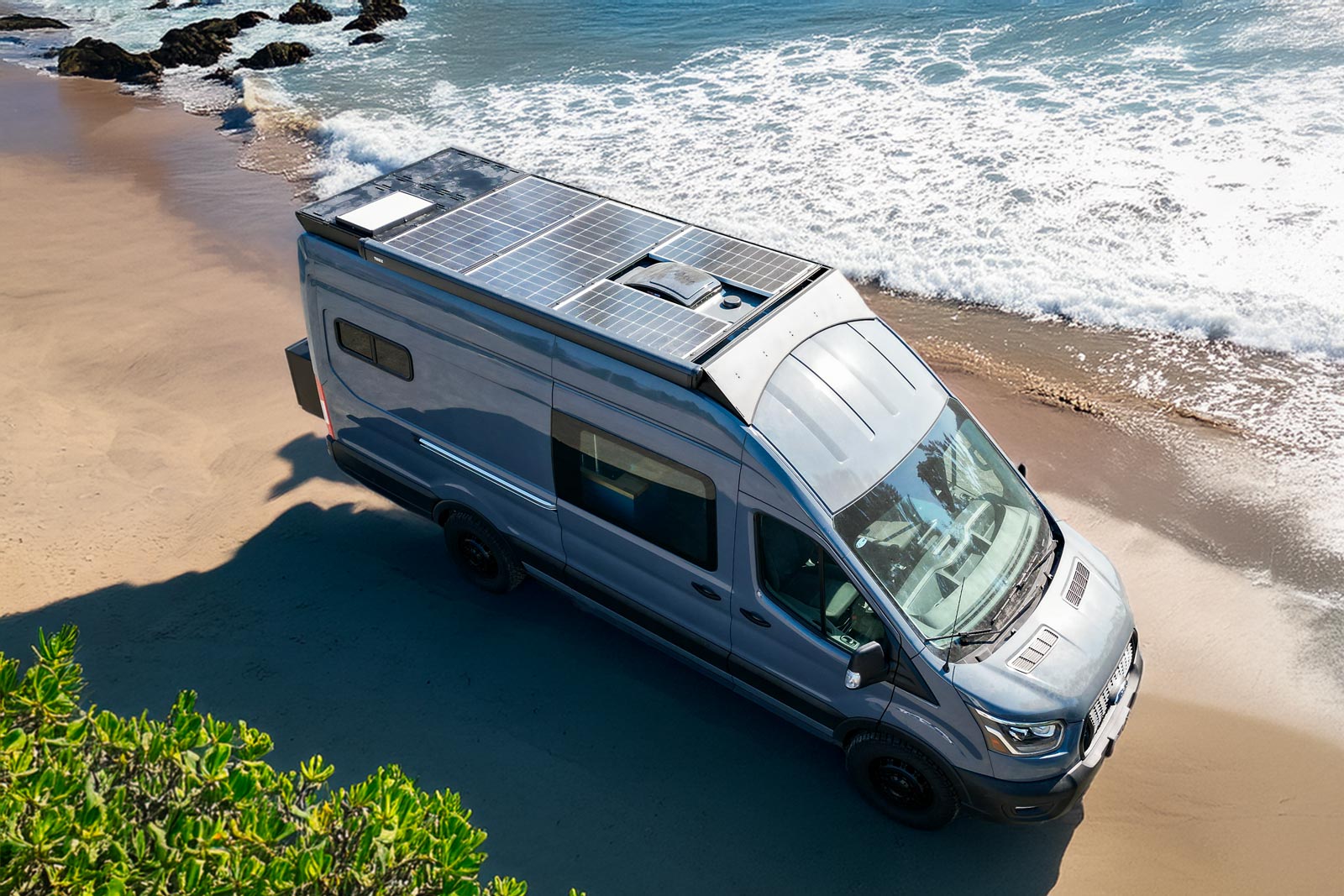 Ford Transit Roof Rack by Orion Van Gear on beach, featuring 700W solar panels, deck panels, F45S Fiamma awning, Starlink satellite system, and MaxxFan for ultimate overland setup.