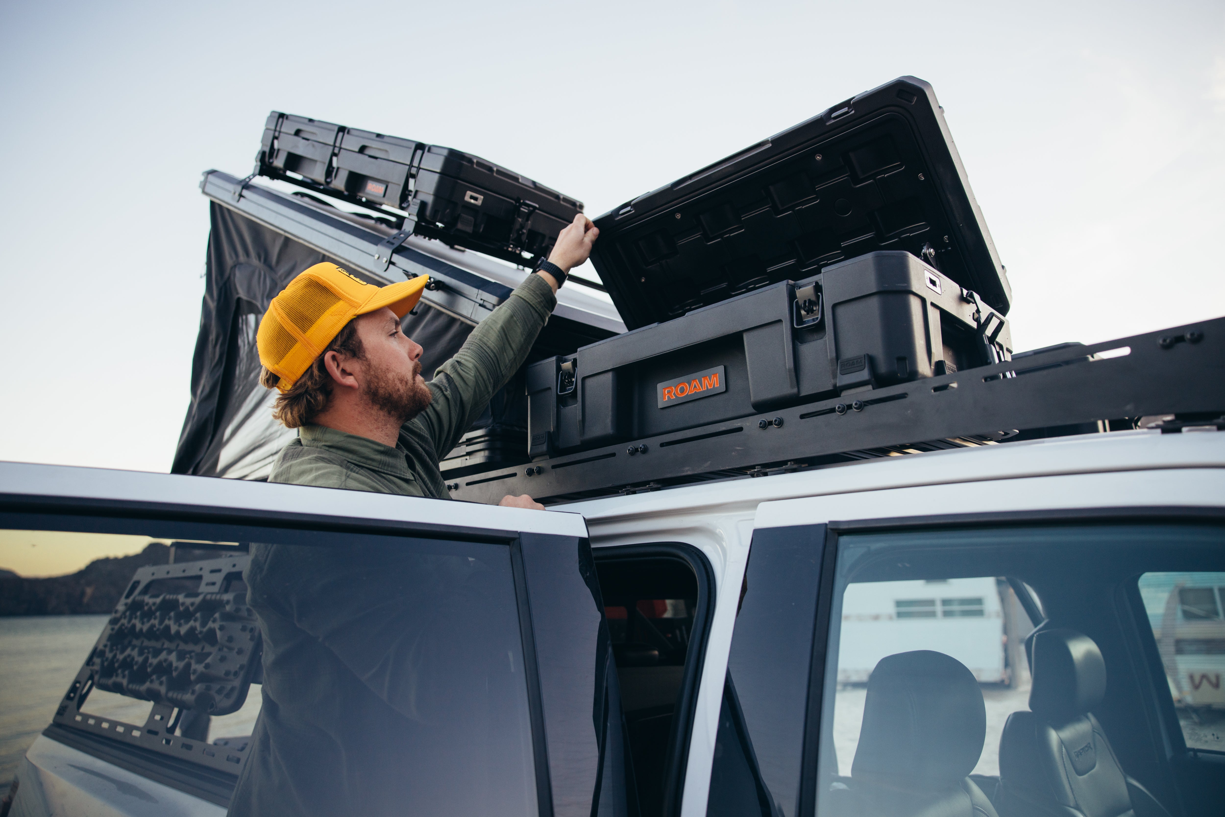 person opening roam 66L case on roof of vehicle