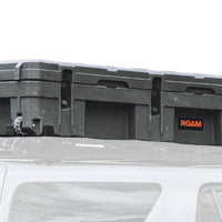 ROAM 128L Rolling Rugged Case mounted on a vehicle roof rack with tie-down points visible
