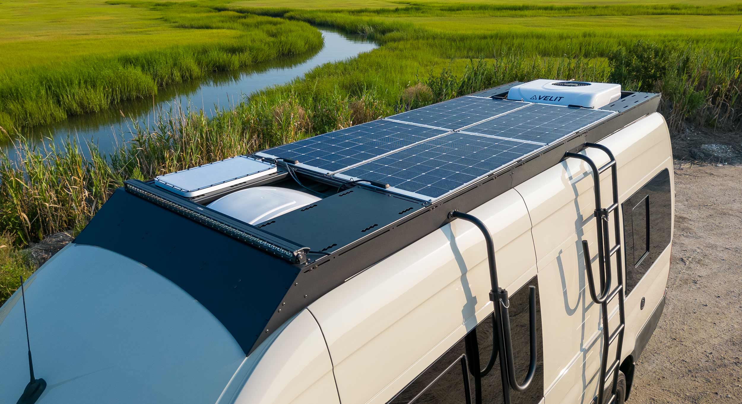 Orion Van Gear Sprinter van with a custom roof rack, solar panels, and adventure-ready equipment, designed for outdoor enthusiasts and van lifers.