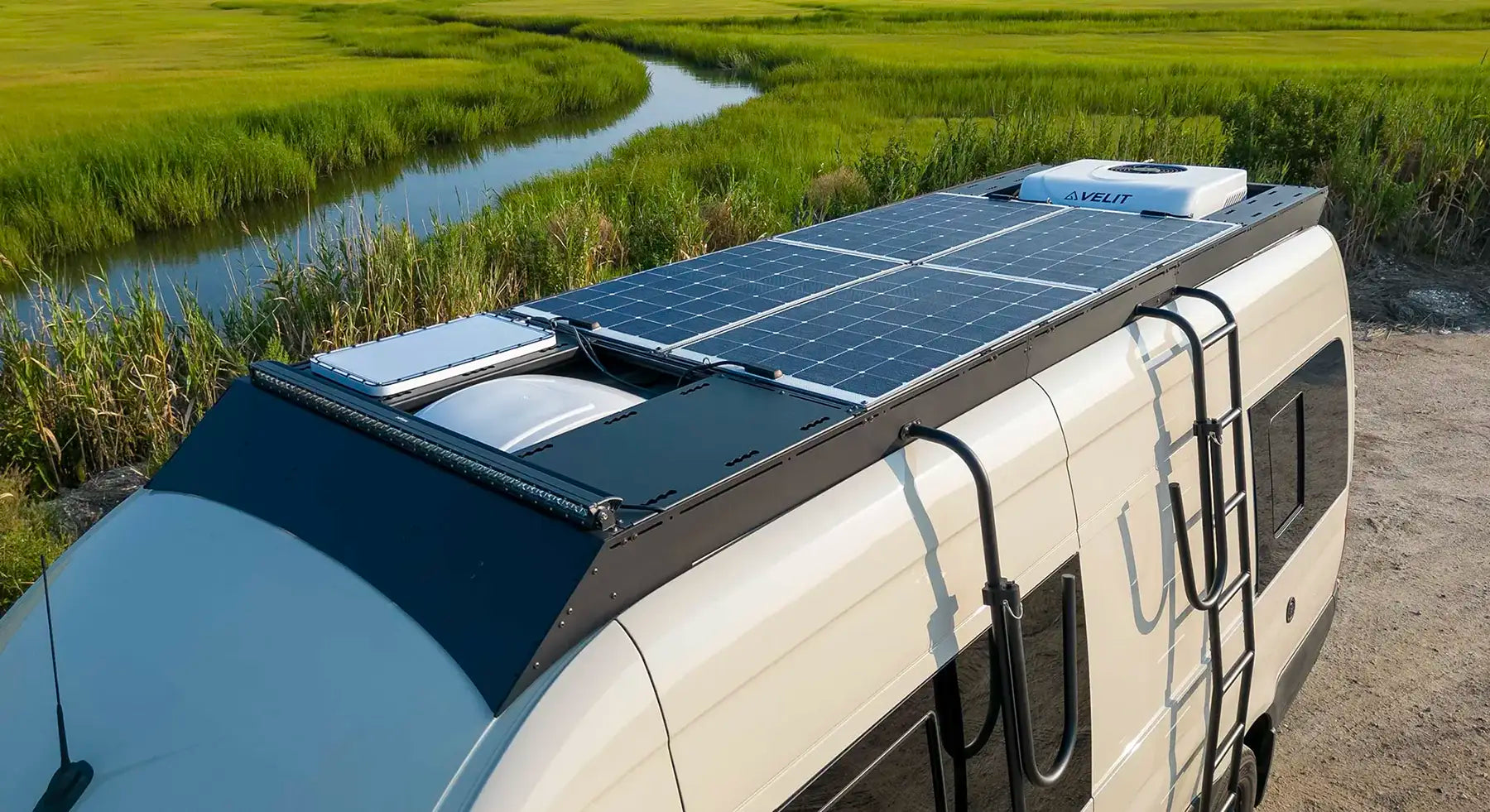 Sprinter Camper van with walk on solar panels on the orion van gear roof rack near a natural landscape