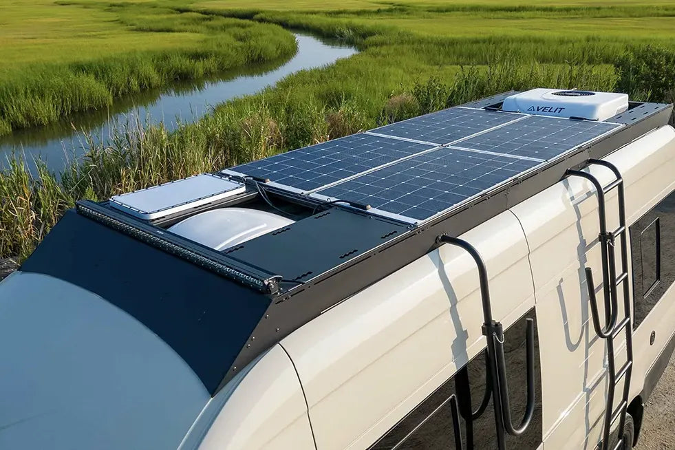Sprinter Camper van with walk on solar panels on an orion van gear roof rack near a natural landscape