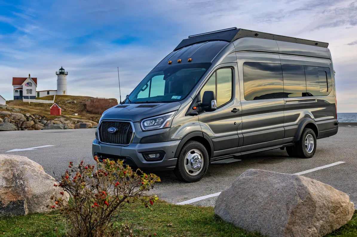 Gray Ford transit van parked near a lighthouse and coastal scenery with orion van gear roof rack, Senna side lights