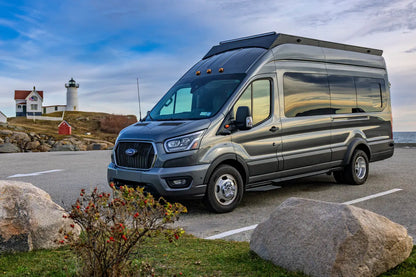Gray Ford transit van parked near a lighthouse and coastal scenery with orion van gear roof rack, Senna side lights