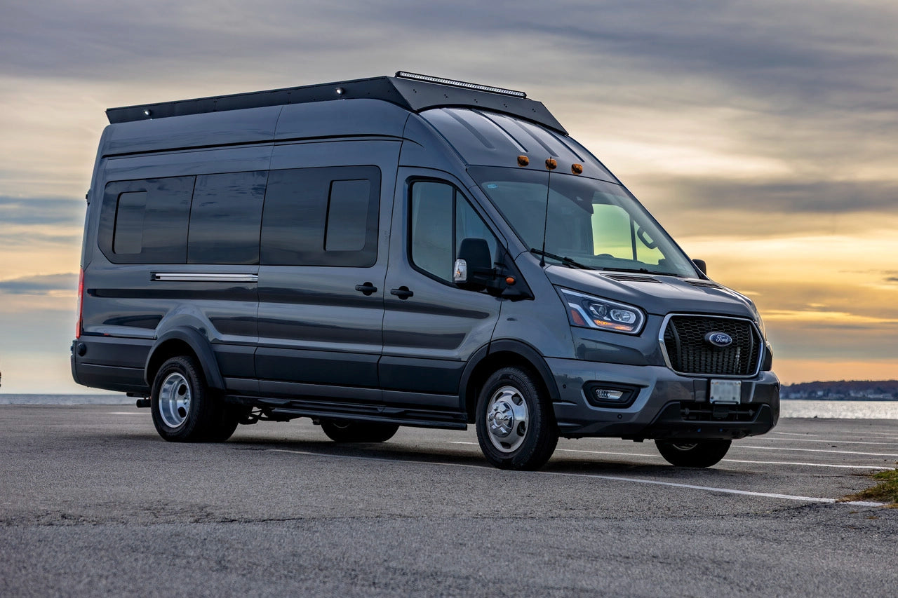 Gray Ford van transit with an orion roof rack on a road with a sunset in the background