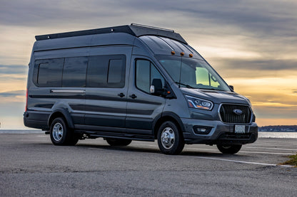 Gray Ford van transit with an orion roof rack on a road with a sunset in the background