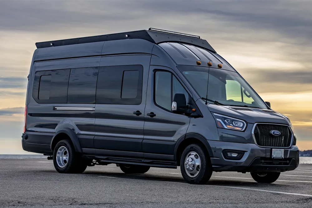 Gray Ford van transit with orion stealth roof rack on a road with a sunset background