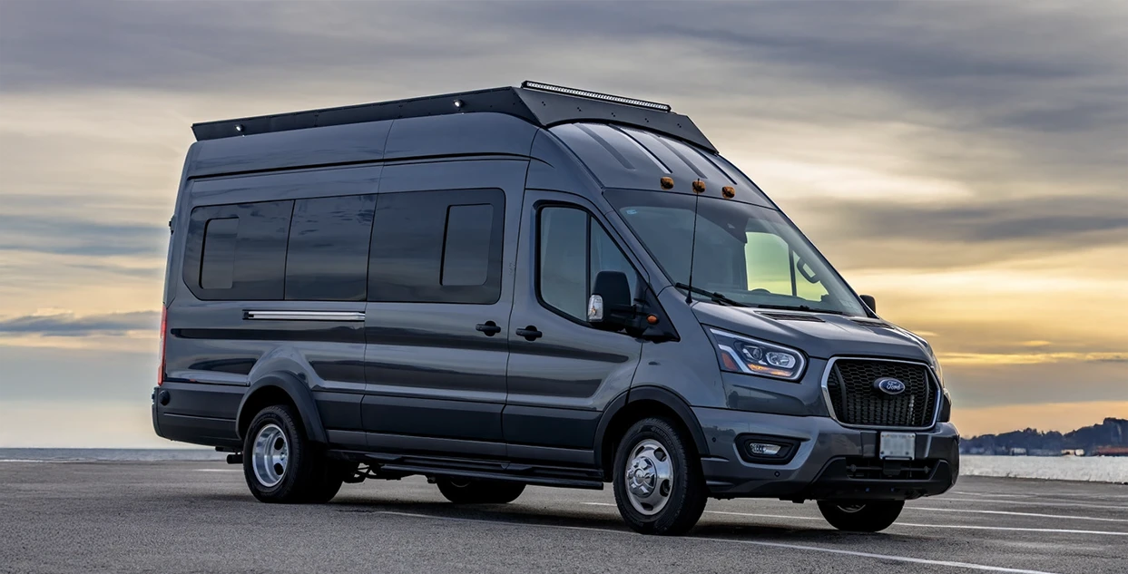 Grey Ford transit van with orion roof rack parked with a sunset background