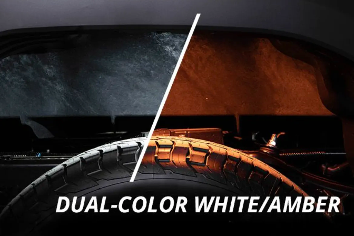 A close-up of a tire with a diagonal split graphic dividing the surface into two finishes: a dark, textured black/gray side and a warm amber-gold side. Large white text at the bottom reads 'DUAL-COLOR WHITE/AMBER'.