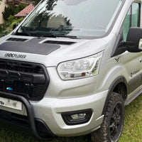 White van with black roof rack on grassy area with trees in the background