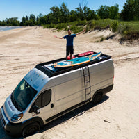 Ram Promaster roof rack by Orion Van Gear, Stealth+ design, perfect for beach adventures with solar panels, decking, and gear storage.