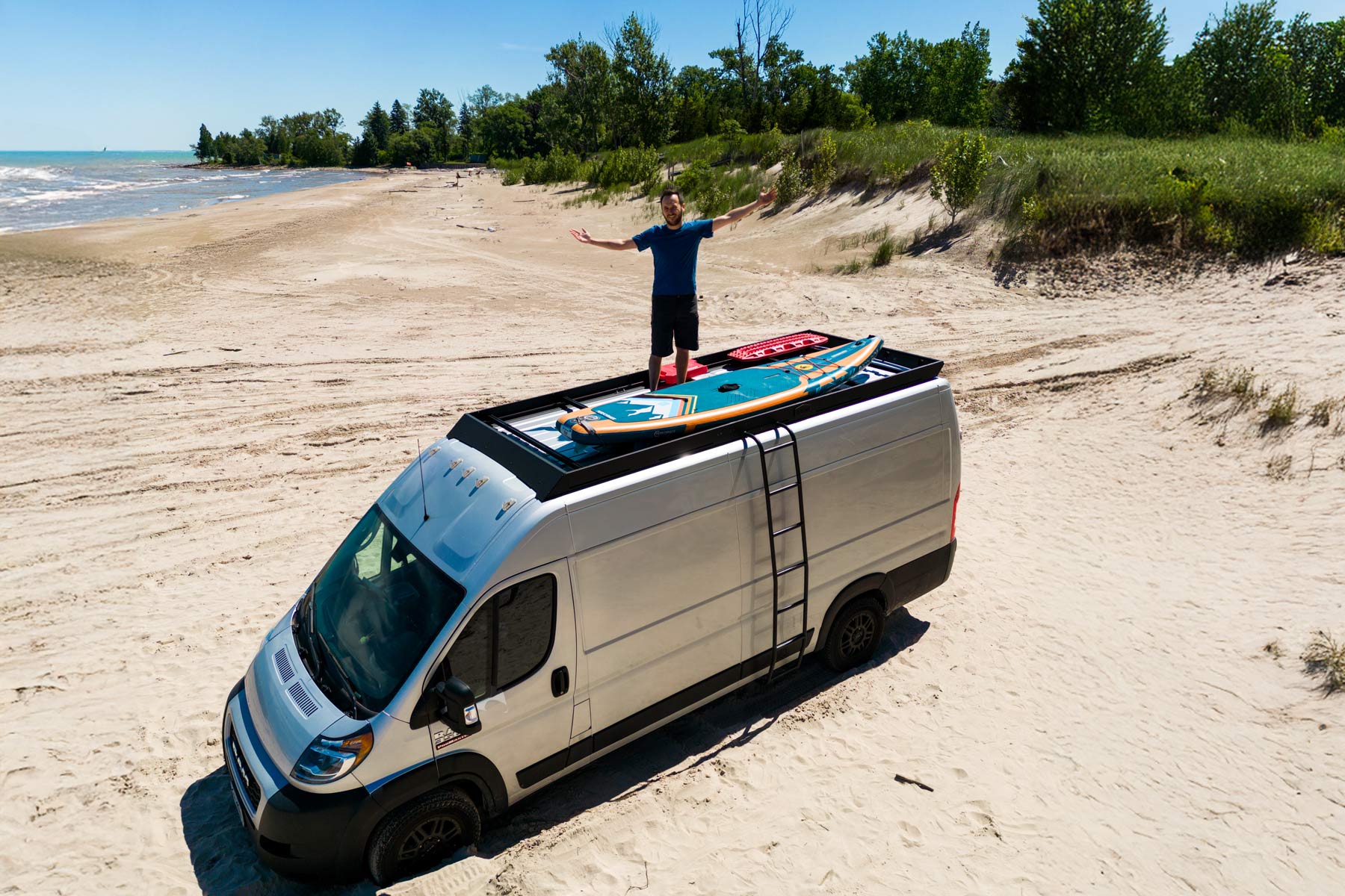 Ram Promaster roof rack by Orion Van Gear, Stealth+ design, perfect for beach adventures with solar panels, decking, and gear storage.