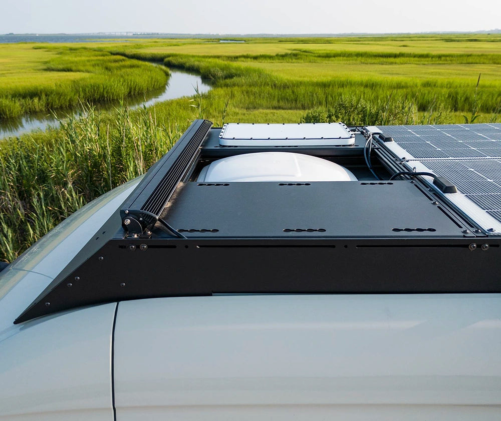 Orion Roof rack system on a sprinter van with a scenic background of green fields and water.