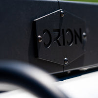 Close-up of the Orion Van Gear logo on a Ram Promaster roof rack, showcasing quality craftsmanship and adventure-ready design
