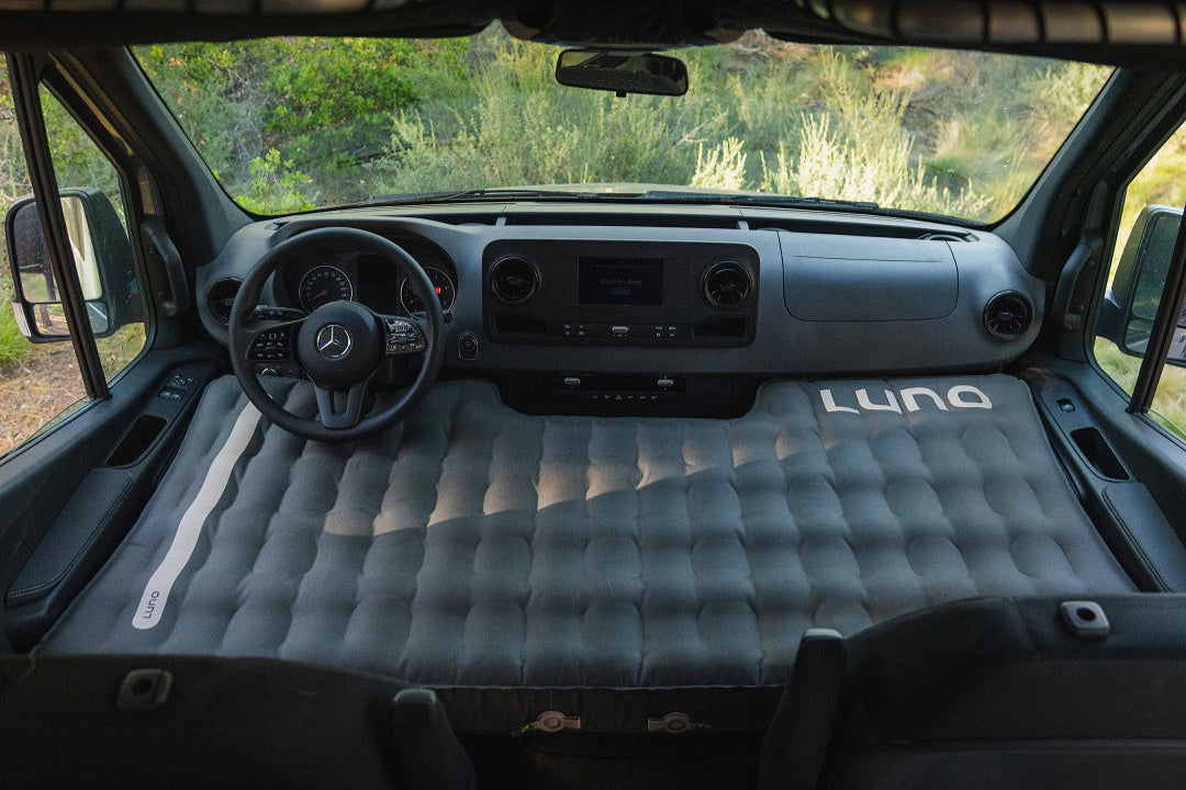 Inflatable mattress in the back of a vehicle with 'Luno' branding.