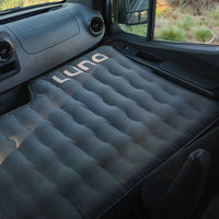 Inflatable mattress in a vehicle with 'Luno' branding, set against a desert landscape.