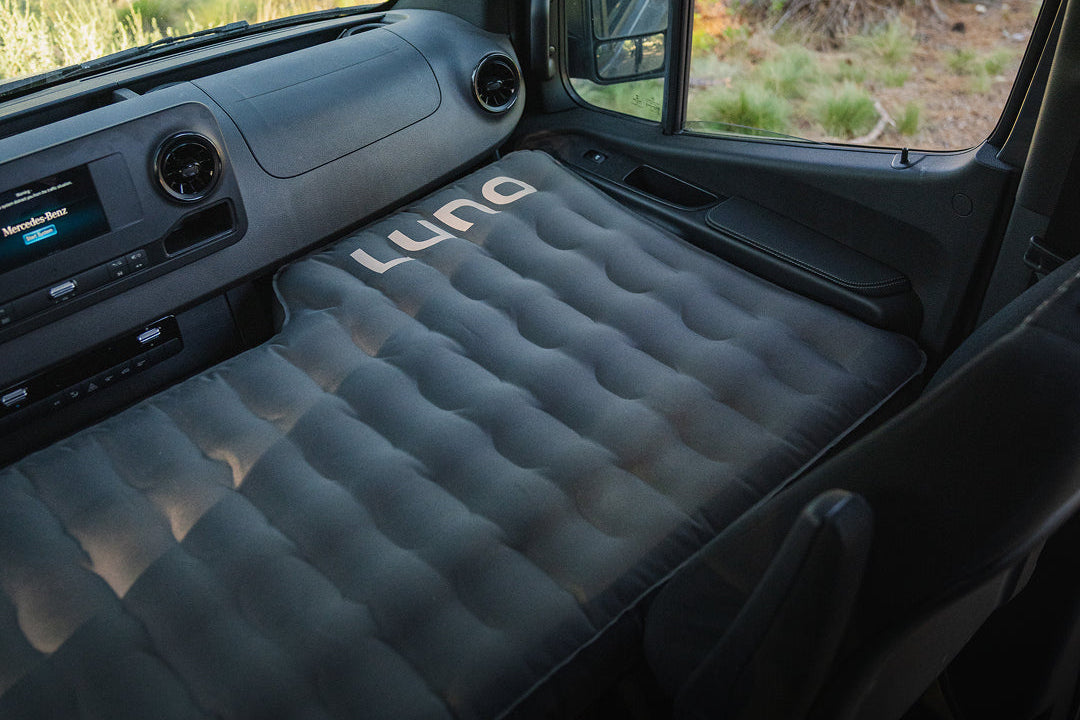 Inflatable mattress in a vehicle with 'Luno' branding, set against a desert landscape.