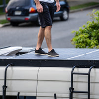 Man walks on walkable solar panels on orion sprinter roof rack