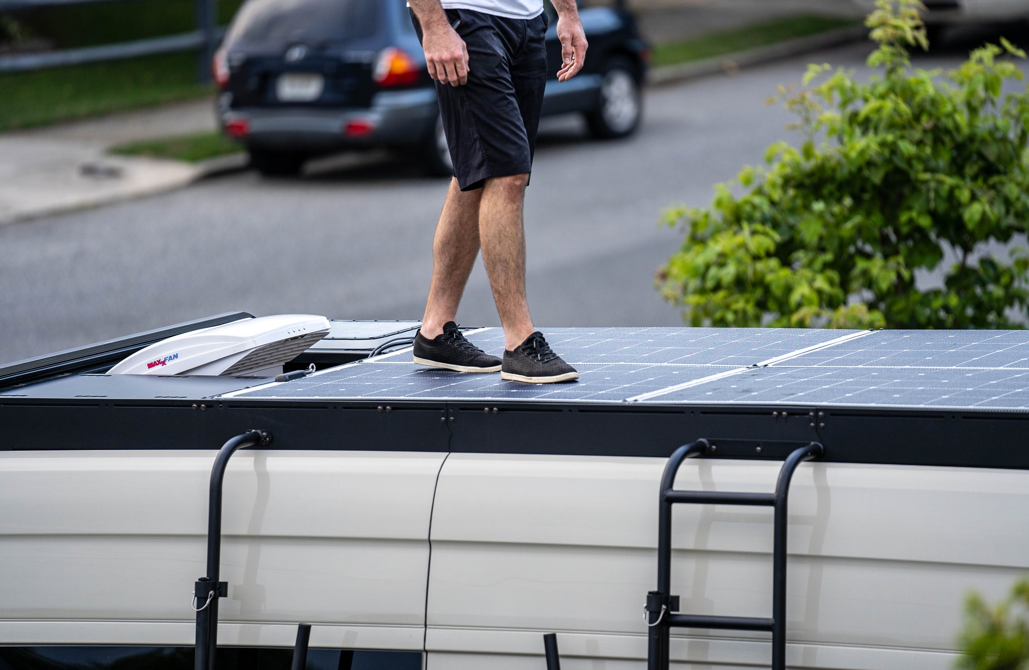 Man walks on walkable solar panels on orion sprinter roof rack