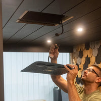 Person installing a nomadic air conditioner faceplate onto wood van ceiling
