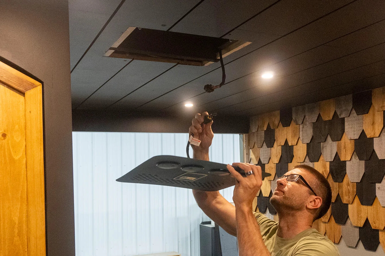 Person installing a nomadic air conditioner faceplate onto wood van ceiling