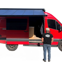 Red van with an extended roof rack and solar panel, person standing nearby wearing a black t-shirt with a logo.