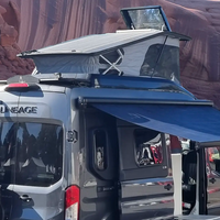 Black off-road vehicle with a roof rack and extended solar awning in a desert landscape.