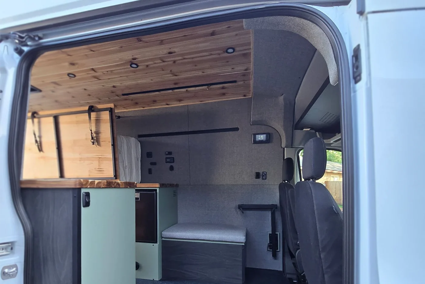 Interior of a van with wooden ceiling and seating area with go code trim kit upholstered
