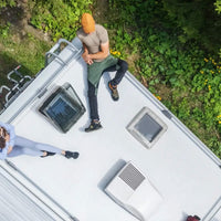Aerial view of an RV roof with skylights installed, showing a camper setup with people relaxing outside