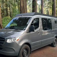 A gray Mercedes-Benz Sprinter Low Standard Roof van parked on a dirt path surrounded by tall redwood trees in a forest with orion van gear roof rack
