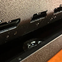 Close-up of a metallic surface with multiple small rectangular cutouts.
