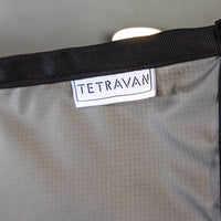 Gray shower curtain with a Tetravan label on a blurred background