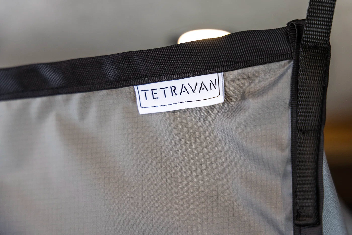 Gray shower curtain with a Tetravan label on a blurred background